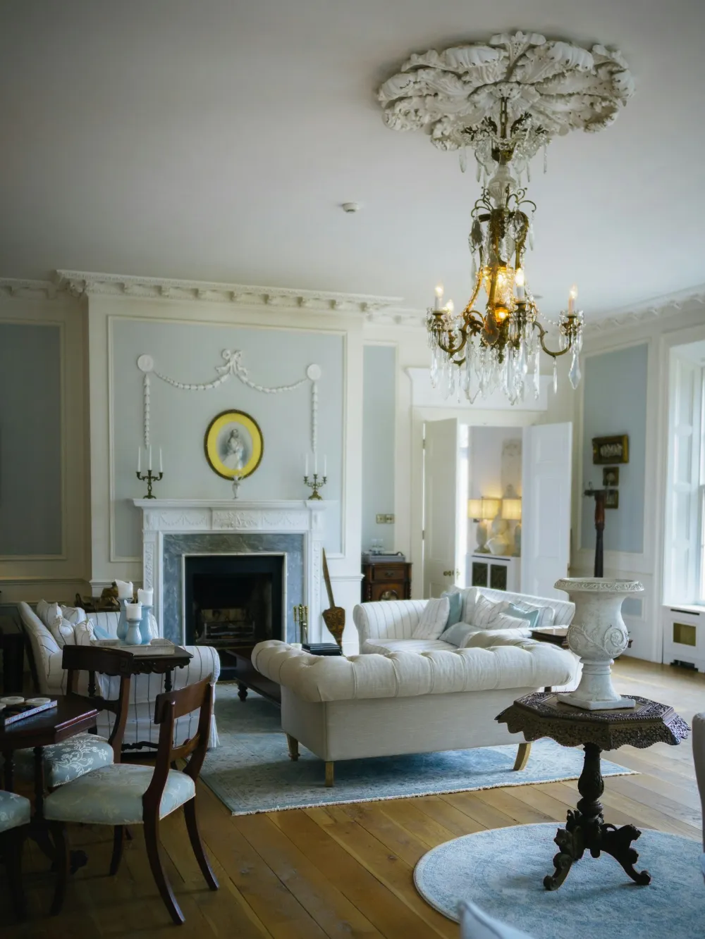 An elegant period drawing room with a marble fireplace, cornicing and a chandelier