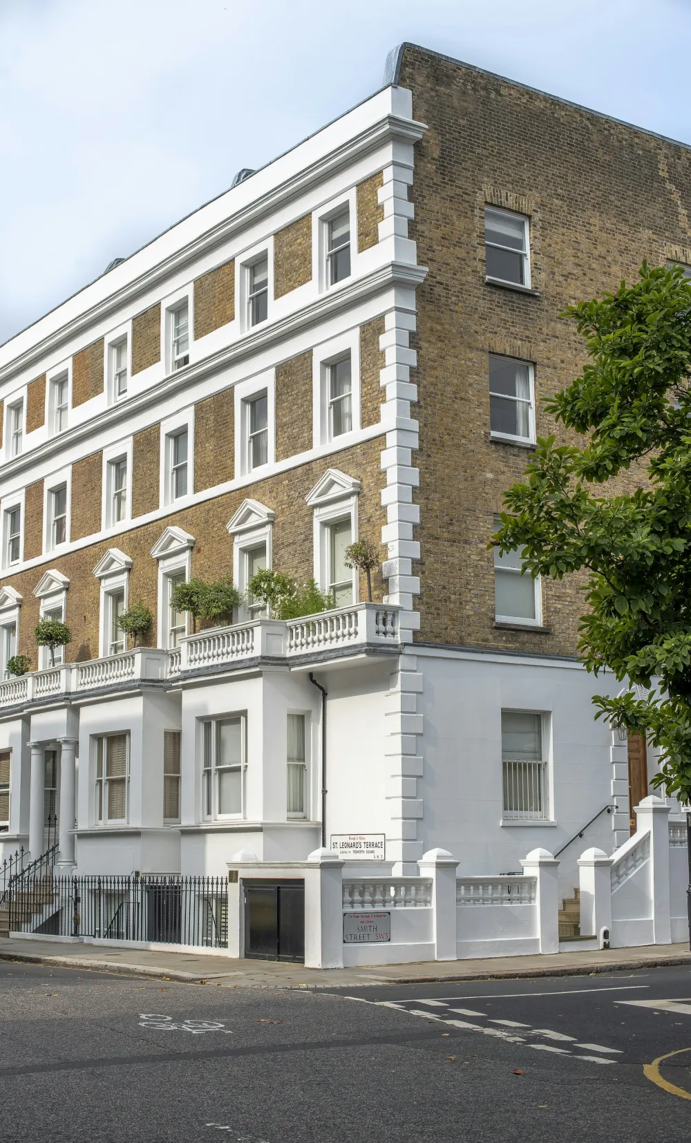 A white-painted London mansion block with sash windows and a balustraded parapet