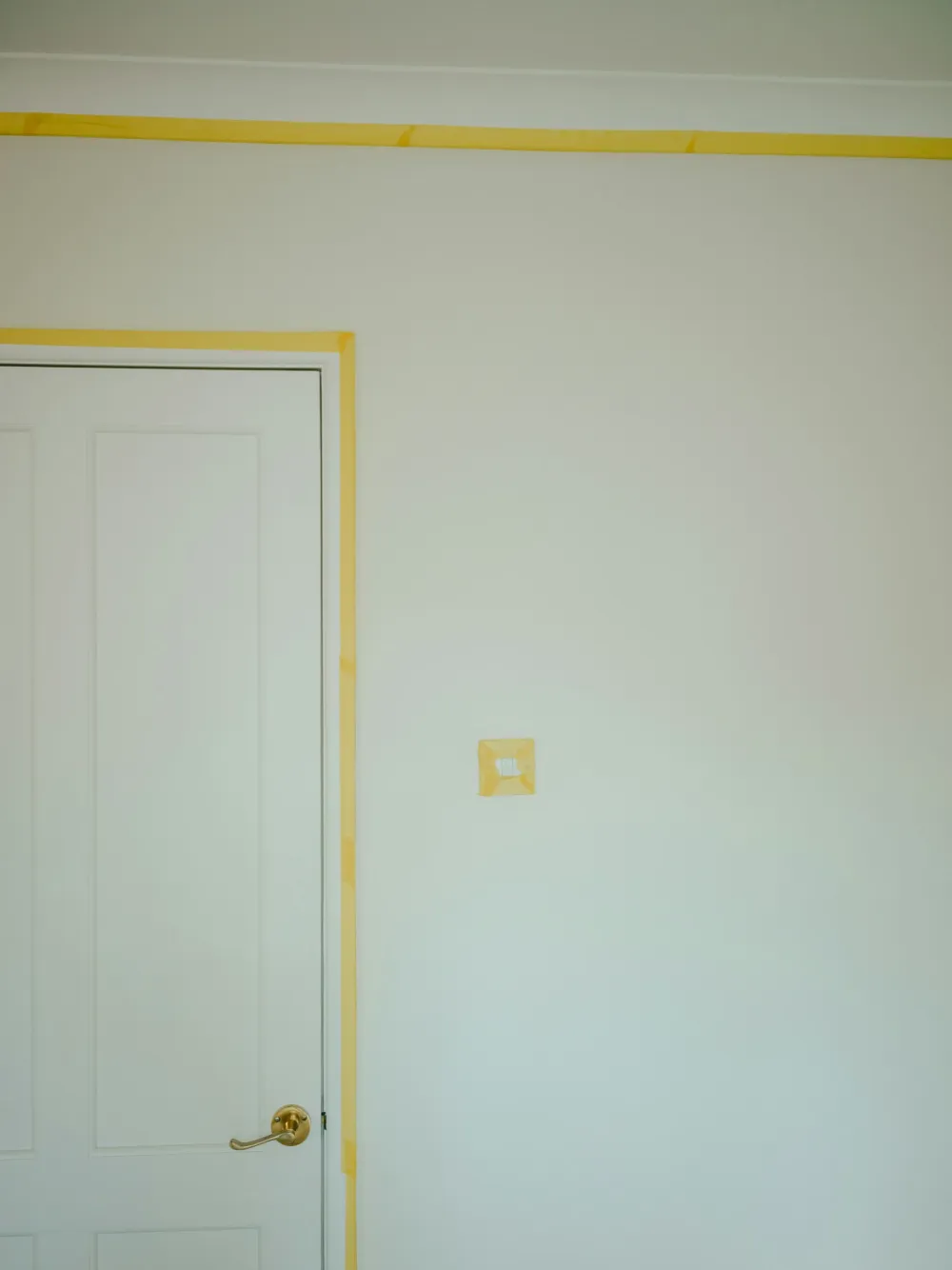 A white panelled door and frame masked with tape ready for painting