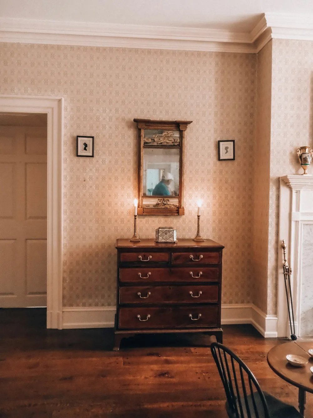 A period hallway with soft peach walls, white panelled doors and an antique chest of drawers