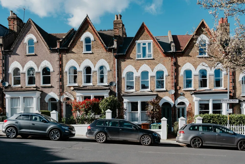 A row of Victorian terraced houses with bay windows and gabled roofs on a London street
