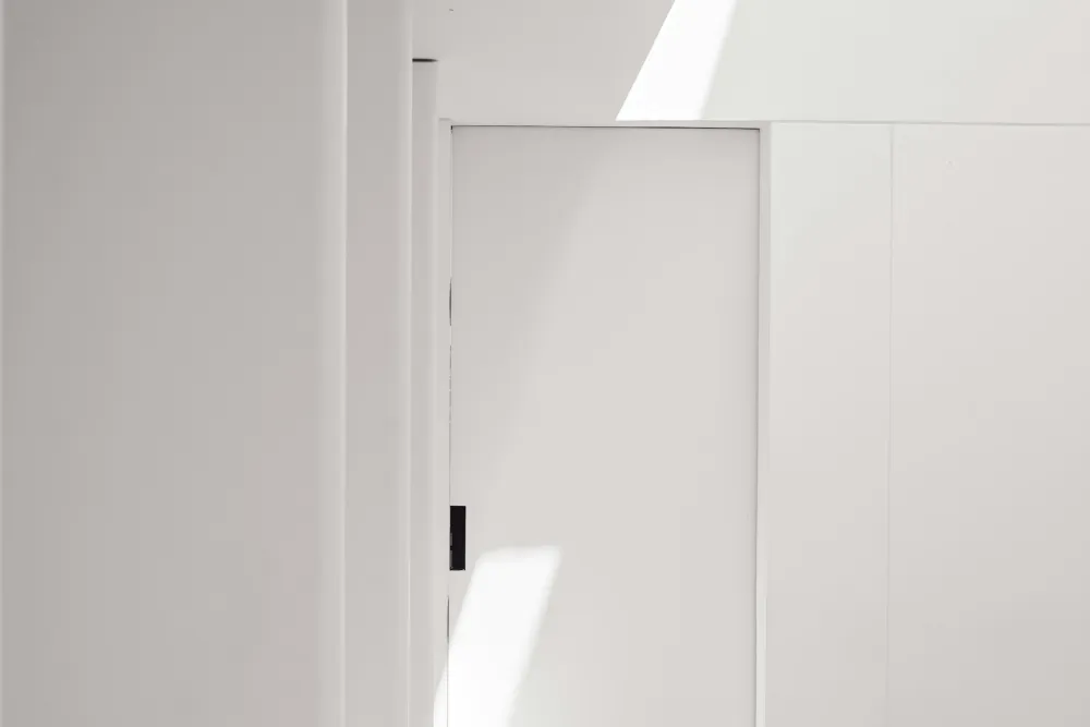 An empty, freshly painted white room with a panelled door and sunlight across the wall